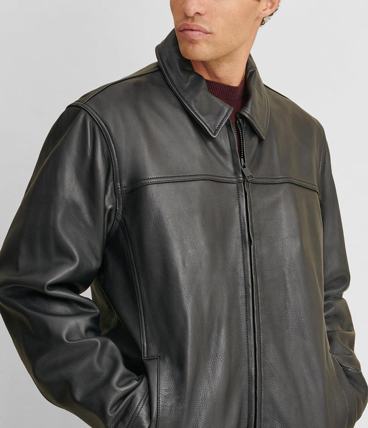 Tilted frontside view of a man wearing a Big & Tall Leather Jacket With Thinsulate Lining and two hand pockets. He also has on a maroon shirt and blue jeans