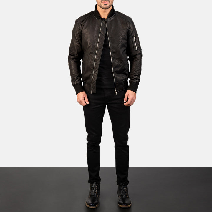 Front Side view of a male model wearing a Black Bomia Ma-1 Leather Bomber Jacket with a standing collar, zipper closure, and rib knit cuffs, paired with a black t-shirt and black pants.