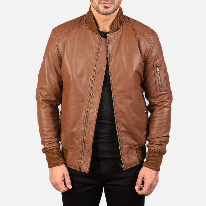 Close up front Side view of a male model wearing a Brown Bomia Ma-1 Leather Bomber Jacket with a standing collar, zipper closure, and rib knit cuffs, paired with a black t-shirt and black pants.