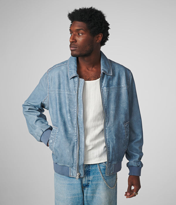 A man wearing a Nash Denim Leather Bomber with a zipper and two welt body pockets, paired with a white rib knit shirt.