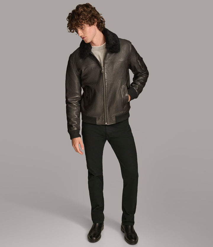 Frontside view of a man wearing Black Ace Bomber Jacket with a fur lining, zipper pockets, and a rib knit collar and closed zipper 