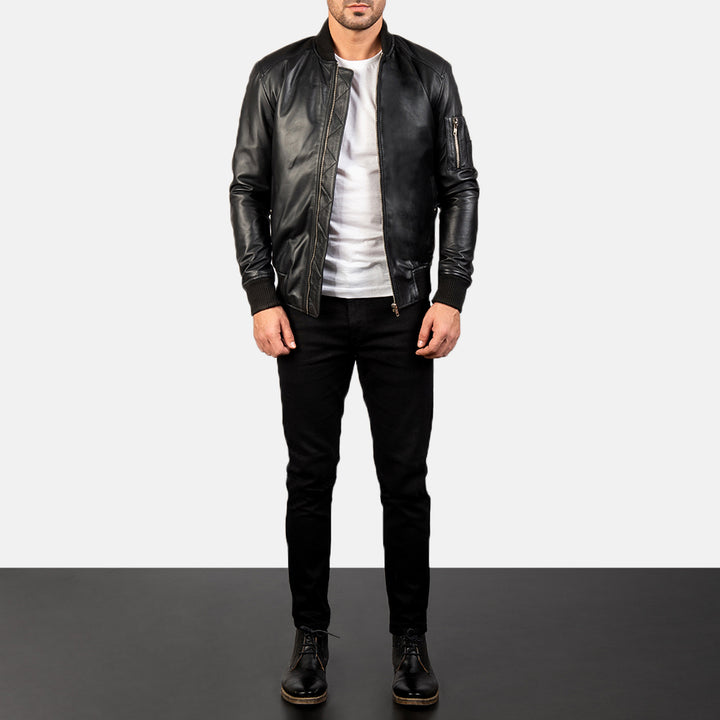Complete front Side view of a male model wearing a Black Bomia Ma-1 Leather Bomber Jacket with a standing collar, zipper closure, and rib knit cuffs, paired with a black t-shirt and black pants.