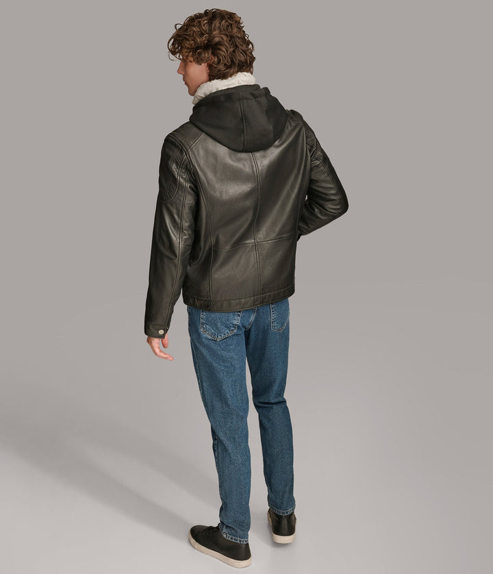 Backside view of a man wearing a Nico Hooded Racer jacket with a standing collar, zipper pockets, and a detachable fleece hood, paired with blue jeans.