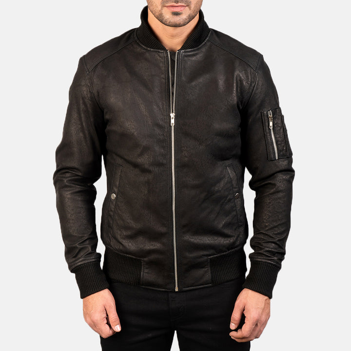 Close up front  Side view of a male model wearing a Black Bomia Ma-1 Leather Bomber Jacket with a standing collar, zipper closure, and rib knit cuffs, paired with a black t-shirt and black pants.
