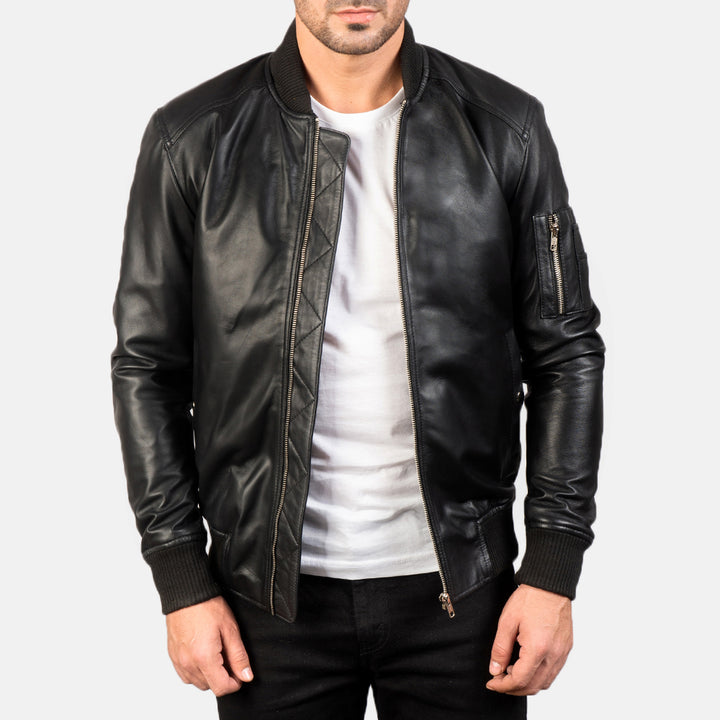 Complete front Side view of a male model wearing a Black Bomia Ma-1 Leather Bomber Jacket with a standing collar, zipper closure, and rib knit cuffs, paired with a white